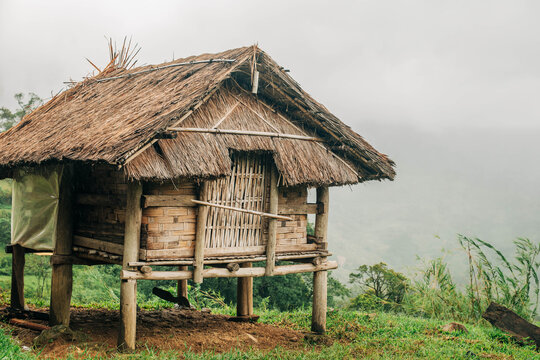 Close view of a traditional bamboo hut with a thatched roof on a green mountain slope