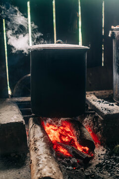 Large metal cooking pot steaming over a wood fire in a rustic kitchen