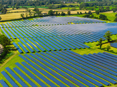 Aerial view of Lisburn Solar Farm featuring rows of photovoltaic panels set within lush green fields in the countryside, Lisburn, Northern Ireland, United Kingdom.