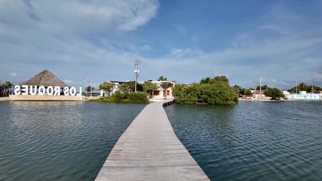 POV walking on wooden pier towards Los Roques sign in Gran Roque