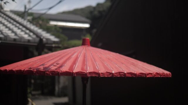 Traditional red paper umbrella in soft focus, outdoors in a Kyoto alleyway