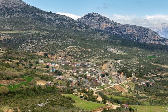 Aerial view of a small village nestled in the mountainous landscape of the Taurus Mountains with a railway line running through the valley in Karaisali, Adana, Turkey.