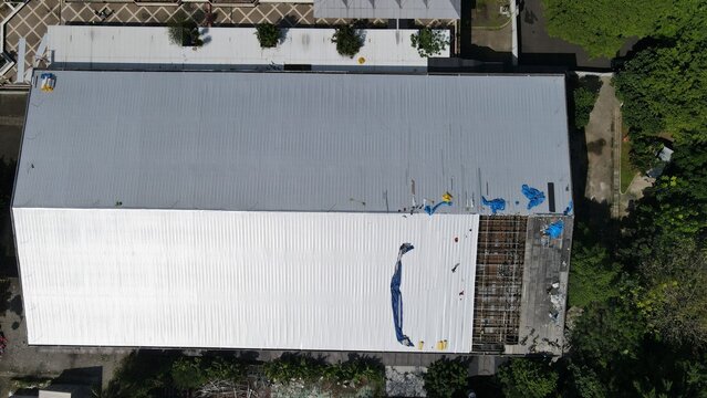 Aerial view of Pertamina Arena in Simprug showing the large metal roof with sections under repair and surrounding greenery in Kecamatan Kebayoran Lama, Daerah Khusus Ibukota, Indonesia.