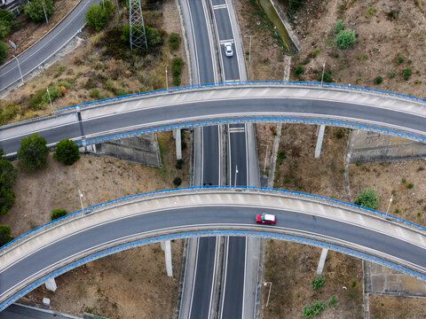 Aerial view of the A5 highway interchange with curved overpasses, concrete pillars, and cars driving through the landscape in Cascais, Lisboa, Portugal.