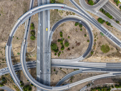 Aerial view of the A5 highway interchange with circular ramps and sparse vegetation in Cascais, Lisboa, Portugal.