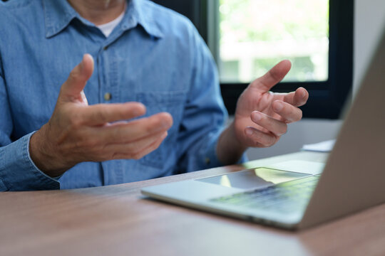Professional man gestures while joining a video call on a laptop at home, representing remote work, online business meetings, virtual communication, teamwork and digital collaboration.