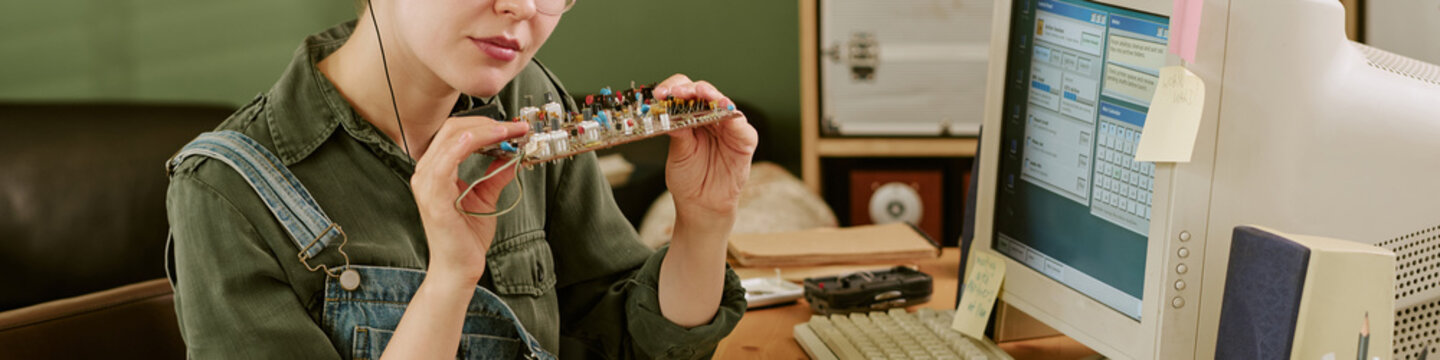 Header of young adult Caucasian woman holding circuit board in retro office next to vintage computer. Image represents vintage technology and engineering, suitable for tech history articles