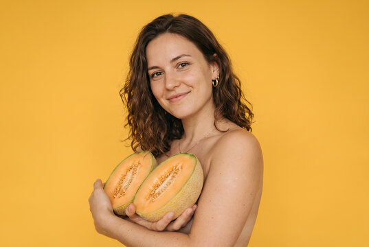 Young woman holding melon halves yellow background studio portrait beautiful