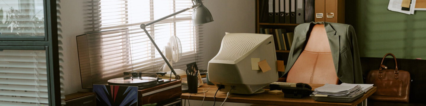 Header of empty retro office workspace featuring vintage computer monitor on wooden desk with turntable and office supplies. Ideal for nostalgic corporate marketing and business history campaigns