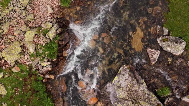 Mountain stream flowing over rocky riverbed from above