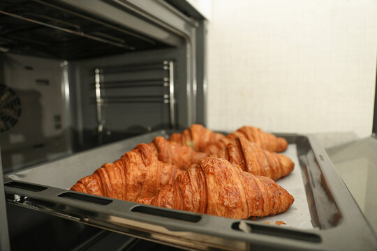 Golden brown croissants rest on tray in oven after baking