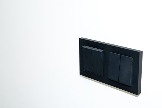 Black light switches mounted on pale wall highlight elegant design. Modern home concept