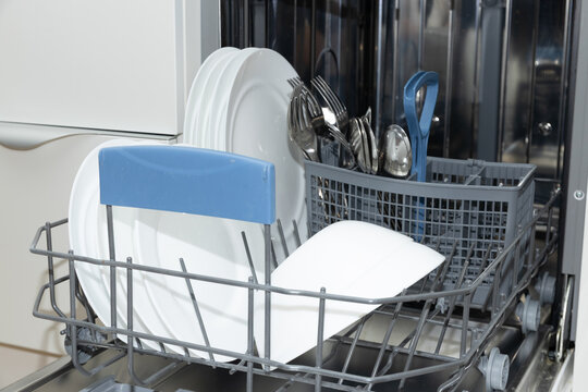 Clean plates and silverware organized in dishwasher ready for use