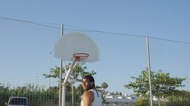 Young man with braids shooting basketball outdoors