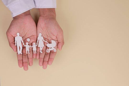 Caring hand holding paper family cutout shows love, protection, safety, care, insurance, support and trust for secure home life