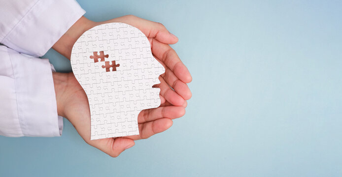 Caring hand holding paper head puzzle with missing brain piece shows hope for health care, psychology research and mental support