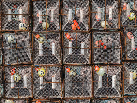 Aerial view of stacked wire mesh crab traps with colorful buoys and fishing gear in Unalaska, Alaska, United States.