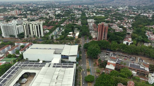 Stunning drone video captures the bustling urban cityscape of Cali at Calle Novena with Calle 50 Sur, featuring tall buildings, greenery, and busy avenues under soft daylight.