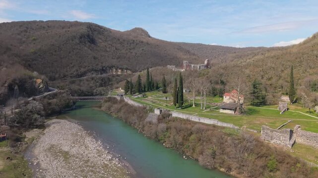 Aerial drone orbit unveiling the historic Nokalakevi Fortress in western Georgia, surrounded by vibrant spring greenery, rolling lush hills, and ancient stone ruins in Samegrelo.