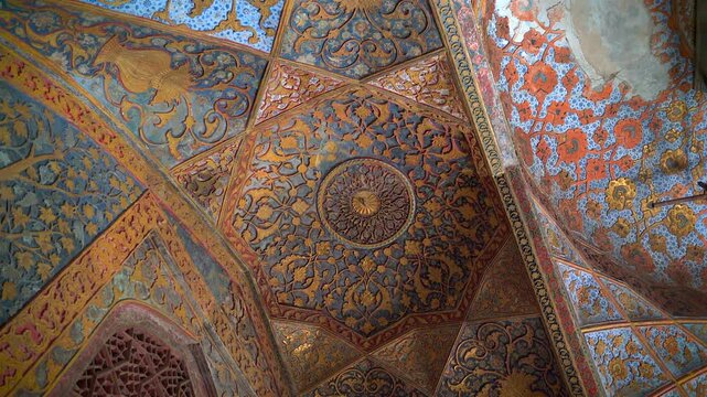 Static looking up shot of ornate gold and blue painted floral frescoes on the vaulted ceiling inside Akbars Tomb in Sikandra near Agra, India.