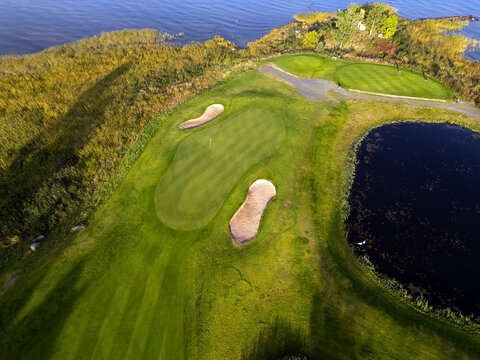 Aerial view of Virpiniemi Golf course featuring a putting green, sand bunkers, and a small pond surrounded by coastal reeds and lush greenery in Oulu, Pohjois-Pohjanmaa, Finland.