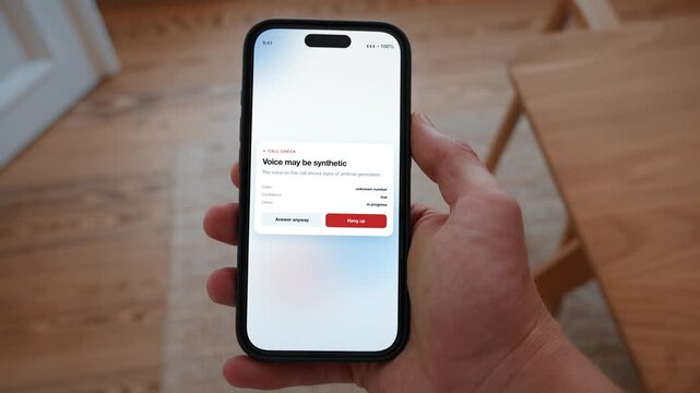 A warning dialog tells the user the voice on the call may be synthetically generated. Point of view shot with the phone held in the hand. Useful for not trusting a voice.