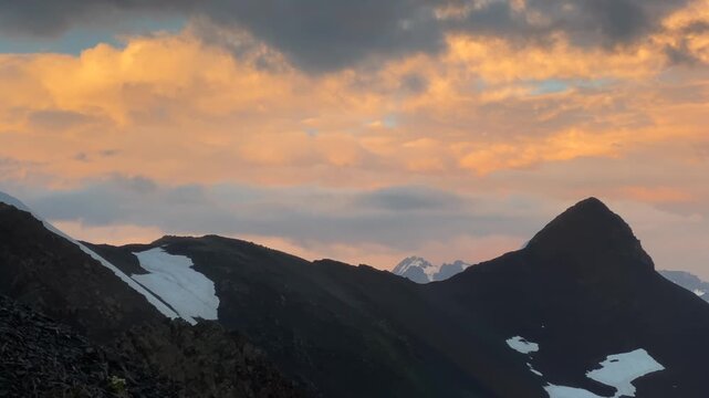 Mountain sunset spreading in wide view over dark ridges and lingering snowfields in Svaneti, Georgia, travel scene for seasonal tourism, destination campaigns, alpine weather media