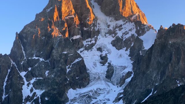 Mount Ushba glowing in close view at sunrise above snowfields in Svaneti, Georgia, mountain scene for climbing destination branding, expedition media, alpine geography, and mountaineering promotion.