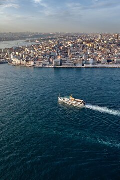 Aerial view of the Golden Horn in Istanbul with a passenger ferry crossing the deep blue water and the historic city skyline in the background, Istanbul, Turkey.