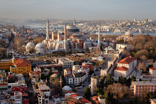 Aerial view of the historic Hagia Sophia mosque with its iconic dome and minarets, surrounded by the dense urban landscape of Fatih, Istanbul, Turkey.