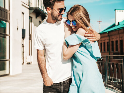 Portrait of smiling beautiful woman and her handsome boyfriend. Woman in casual summer jeans dress. Happy cheerful family. Female having fun. Couple posing on the street background in sunglasses