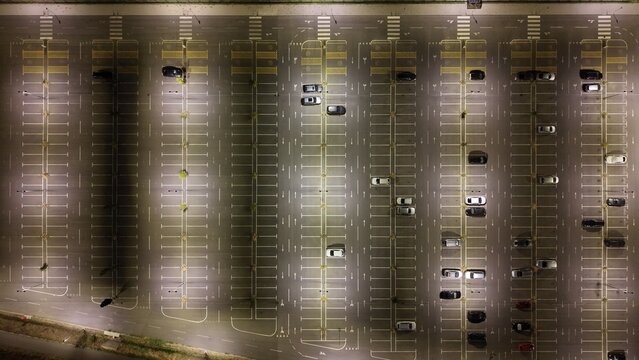 Aerial view of the North Industry parking lot with rows of parked cars illuminated by bright overhead lights at night in Pancevo, Serbia.