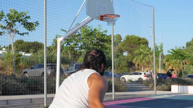 African american man scoring a basket on an outdoor court