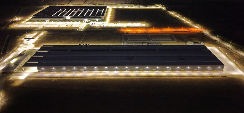 Aerial view of the illuminated ZF Friedrichshafen industrial plant at night with large factory buildings and parking lots in Pancevo, Serbia.