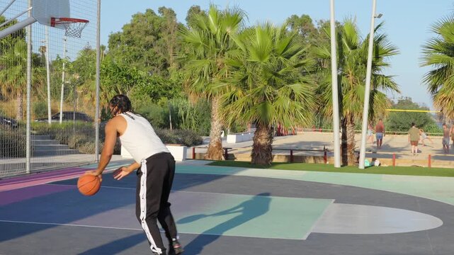 Young athletic man scoring a basket on outdoor court