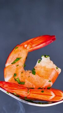 steaming shrimp on spoon with fresh herbs closeup hot seafood dish, vertical video