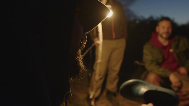 Group of men camping in the wild and gather near the bonfire and talk with each other. Fishermen camping and talk stories at night
