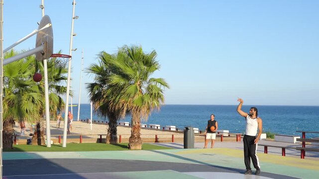 Man scoring a perfect basketball shot by the beach