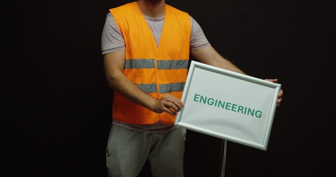Worker in a safety vest straightening an engineering sign until aligned, representing precision, technical work, accuracy, engineering, and professional standards.