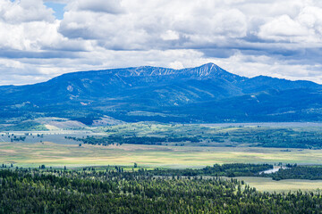 Obraz premium Mountain Valley with a narrow river line beneath a low forested ridge