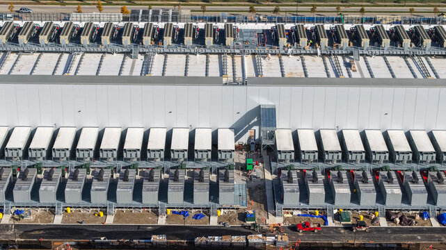 Aerial view of a large data center facility featuring rows of industrial cooling units and HVAC systems on the roof and ground level in New Albany, Ohio, United States.