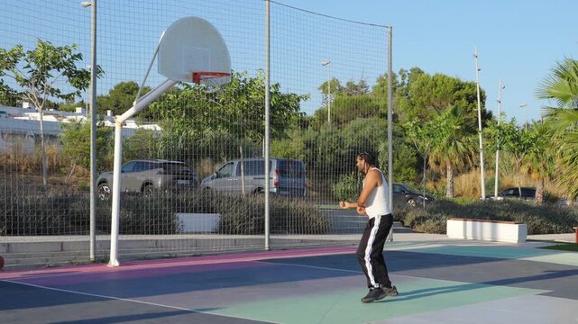 Athletic man playing basketball on an outdoor court