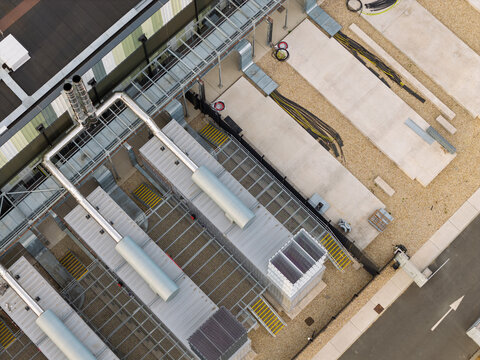 Aerial view of a data center facility with industrial cooling units, metal piping, concrete pads, and a paved road in the United Kingdom.