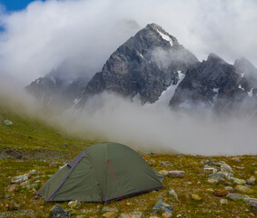 touristic tent stay on the mountain slope in dense mist and clouds, mountain travel scene © Yuriy Kulik