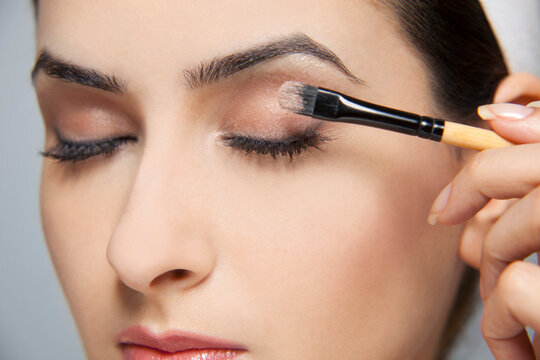Beautiful woman applying eye shadow