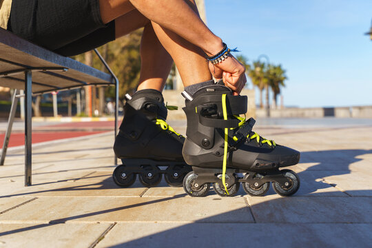 Man tying inline skate laces, preparing for a rollerblading session outdoors