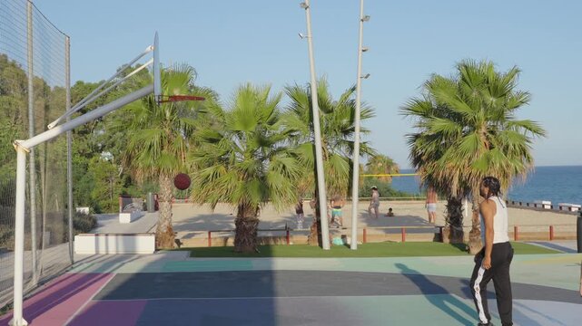 Man scoring a basket on a seaside basketball court