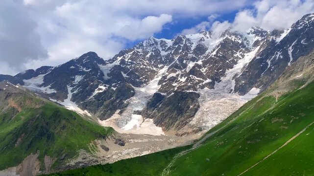 Shkhara Glacier descending in wide view above green alpine slopes near Ushguli, Svaneti, Georgia, travel scene for trekking routes, glacier tourism, mountain geography, and outdoor destination