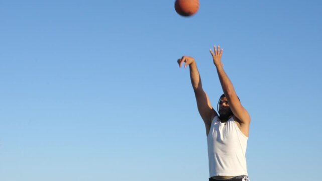 Young athletic man shooting a basketball outdoors