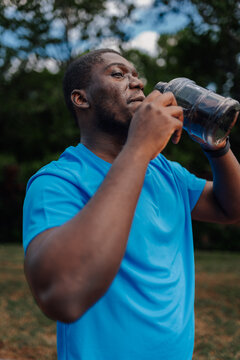 Black man hydrating outdoors after workout